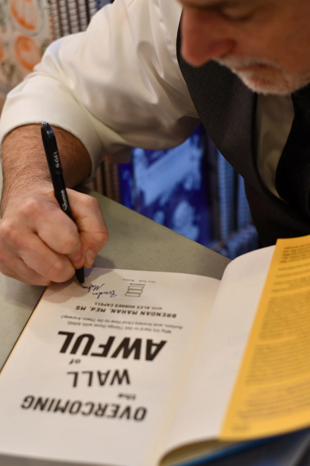 Close-up of Brendan Mahan signing a copy of Overcoming the Wall of Awful