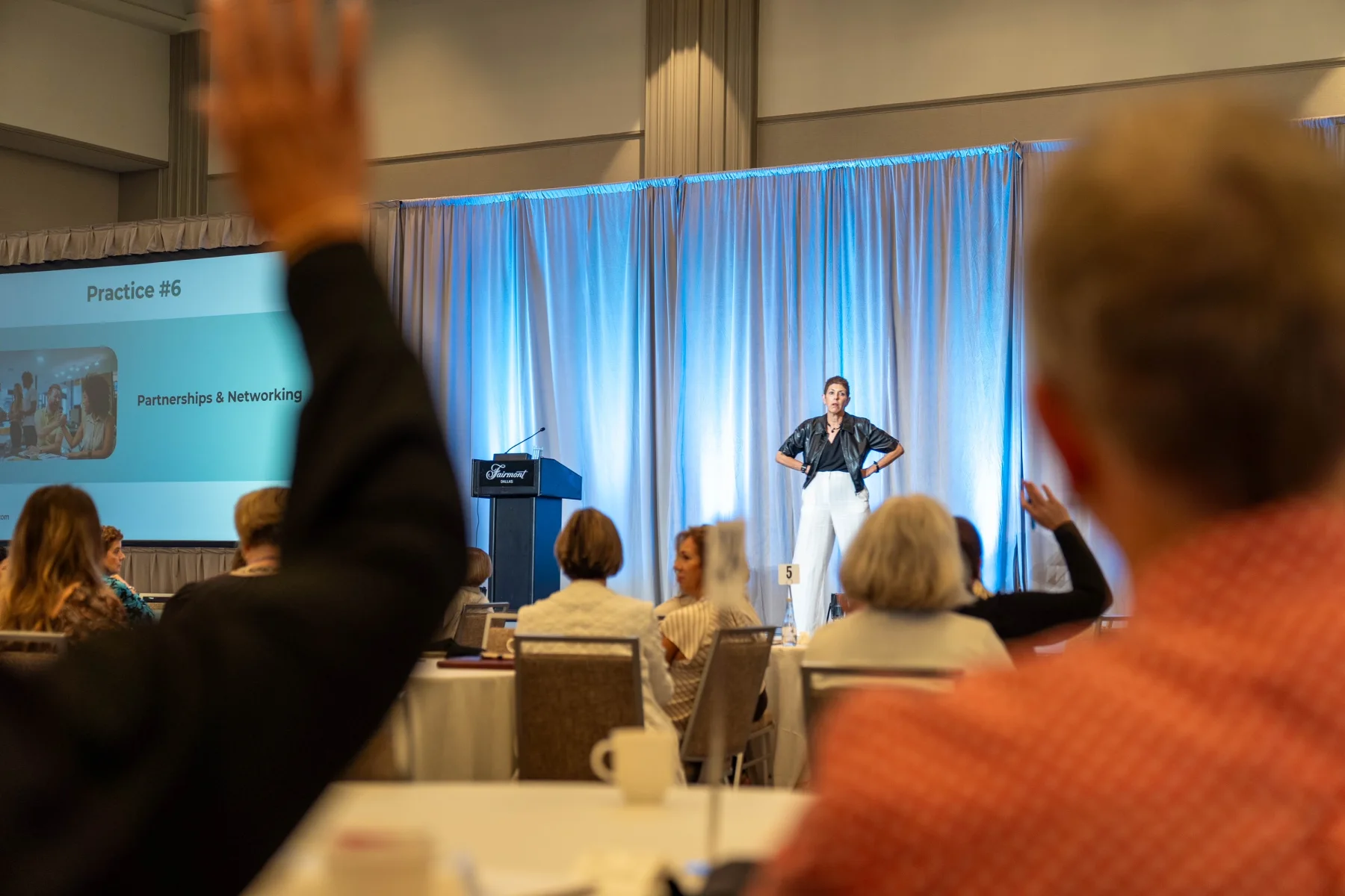Leslie Josel standing onstage in front of an audience during a workshop.