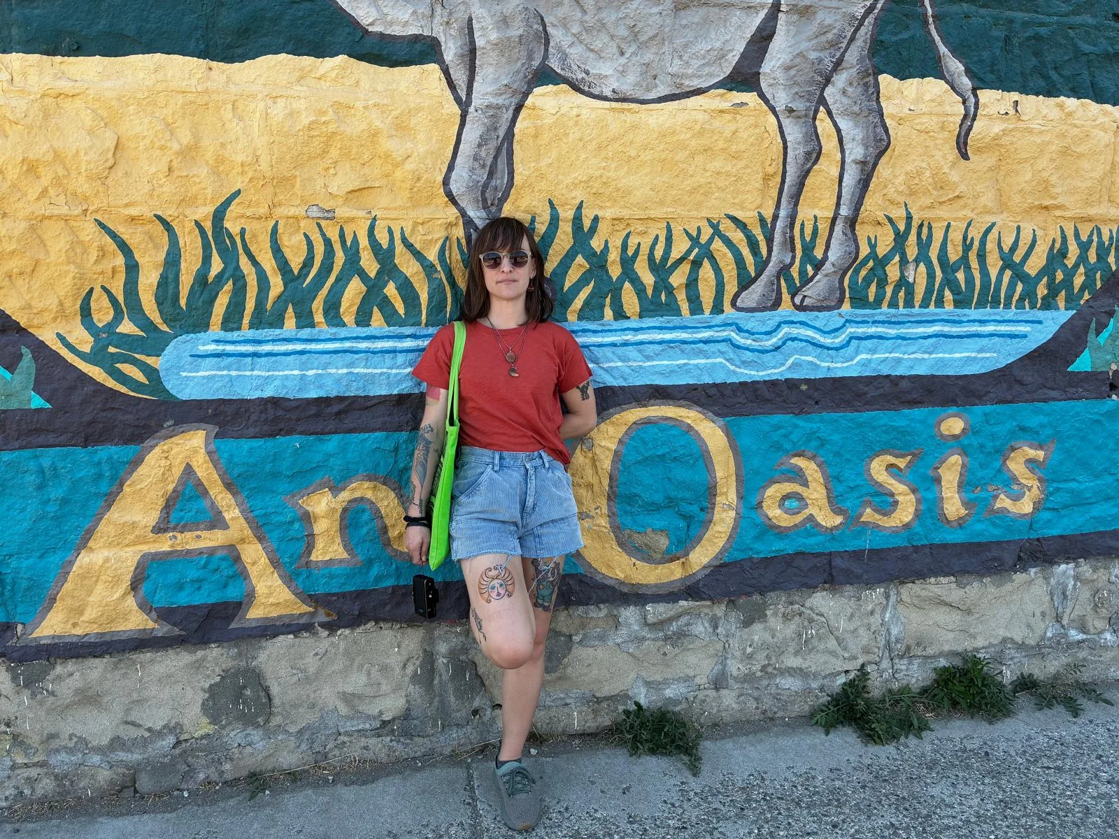 Sarah Teresa Cook standing in front of a colorful mural