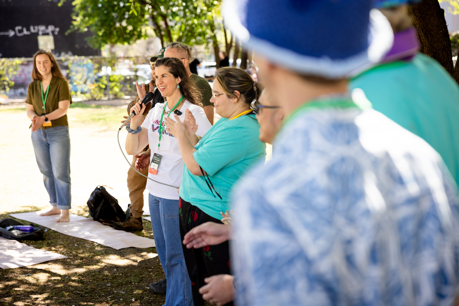 A small group of NeuroDiversion attendees gathered outdoors under trees while one person speaks